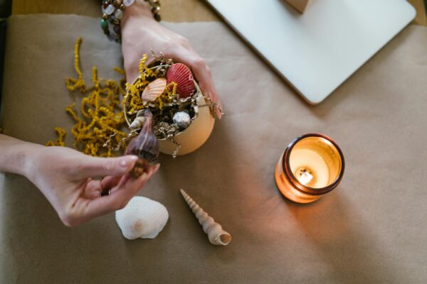 A cozy scene of hands crafting with seashells and candlelight.