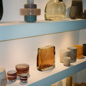 A well-lit arrangement of diverse ceramic and glass vases on shelves.