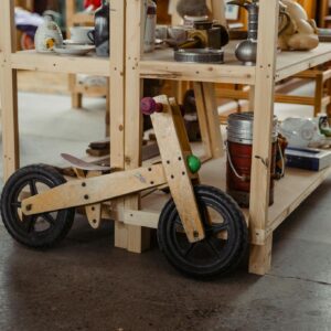 An interior view of an antique shop featuring a rustic wooden toy bike among vintage items.