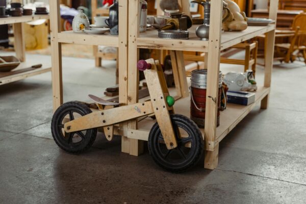 An interior view of an antique shop featuring a rustic wooden toy bike among vintage items.